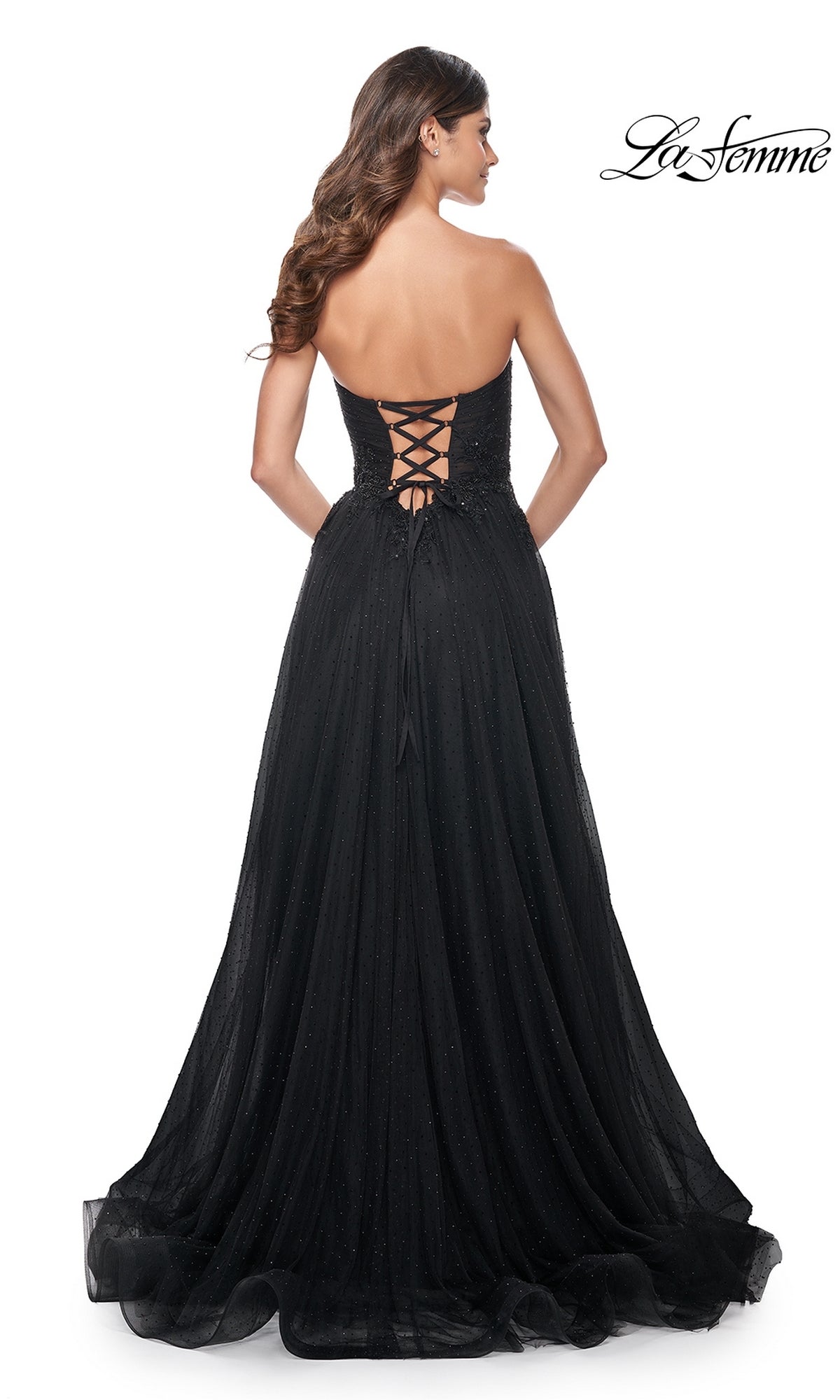 A woman models the La Femme Long Black Strapless Prom Dress 32005, featuring a lace-up back, beaded detailing, and a floor-length A-line skirt for an elegant formal look.